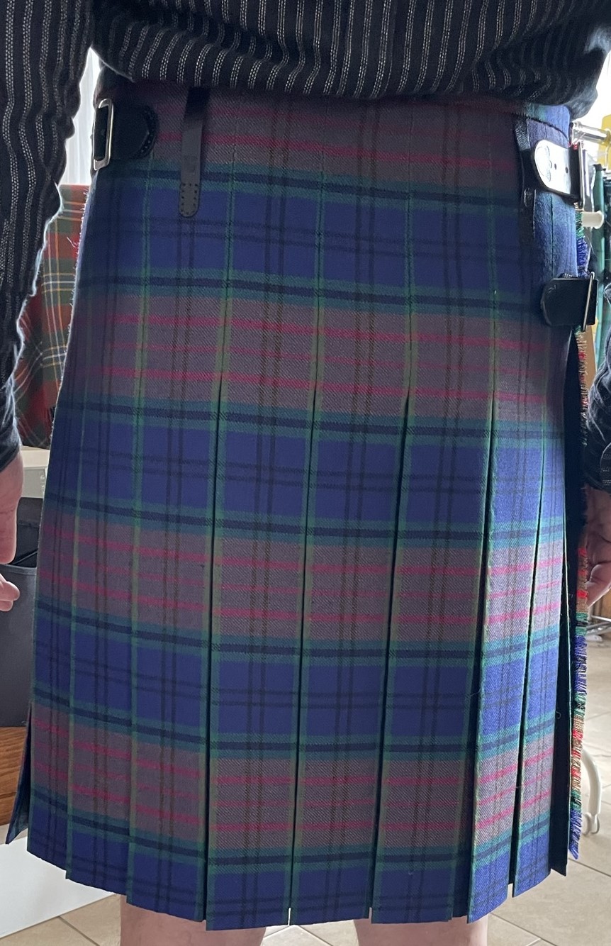 A picture of a man standing in a kilt with a historical box pleat tailored kilt.