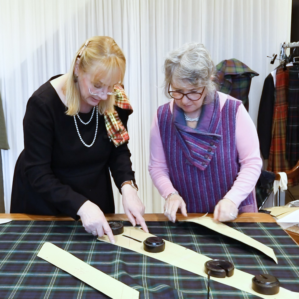 A women being instructed on hand tailoring a kilt by Marion Foster, owner of The College of Master Kilt Tailors.